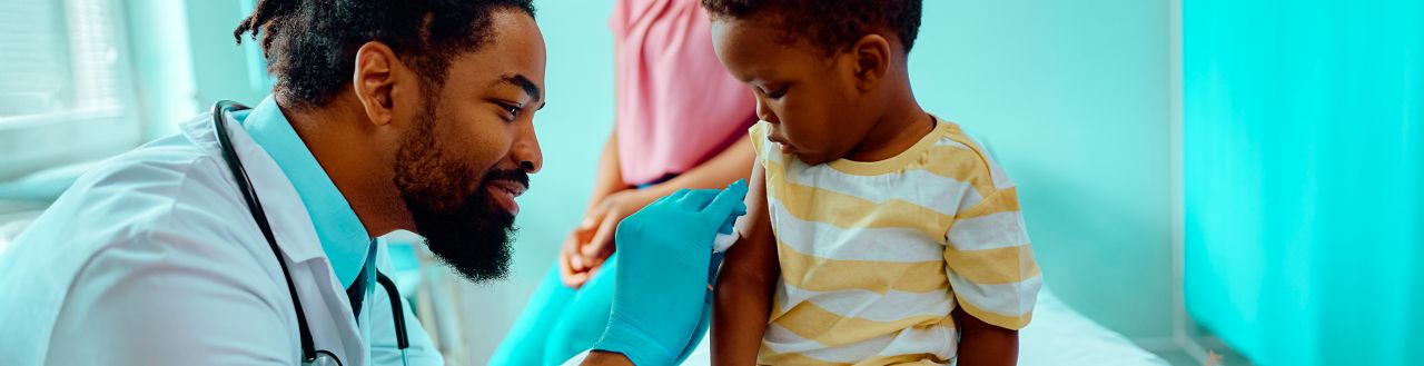 Doctor cleaning of a toddler's upper arm before administering a vaccine
