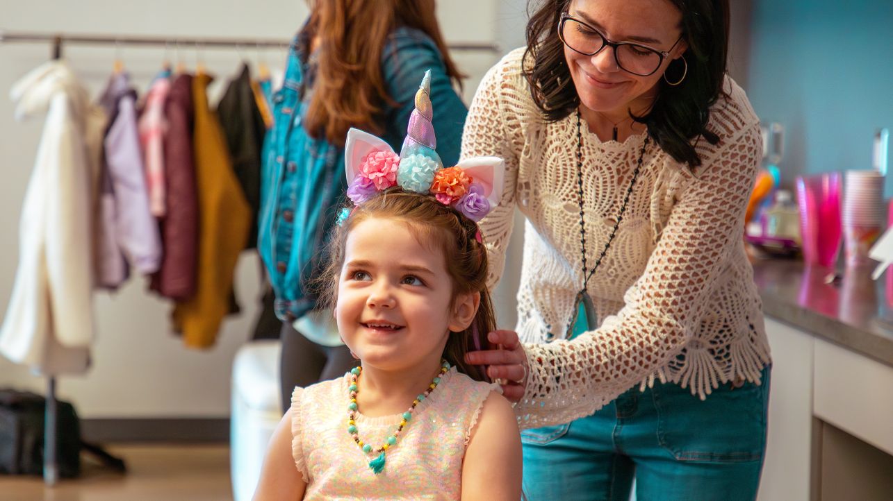 Smiling mother helping to put a necklace on a young daughter