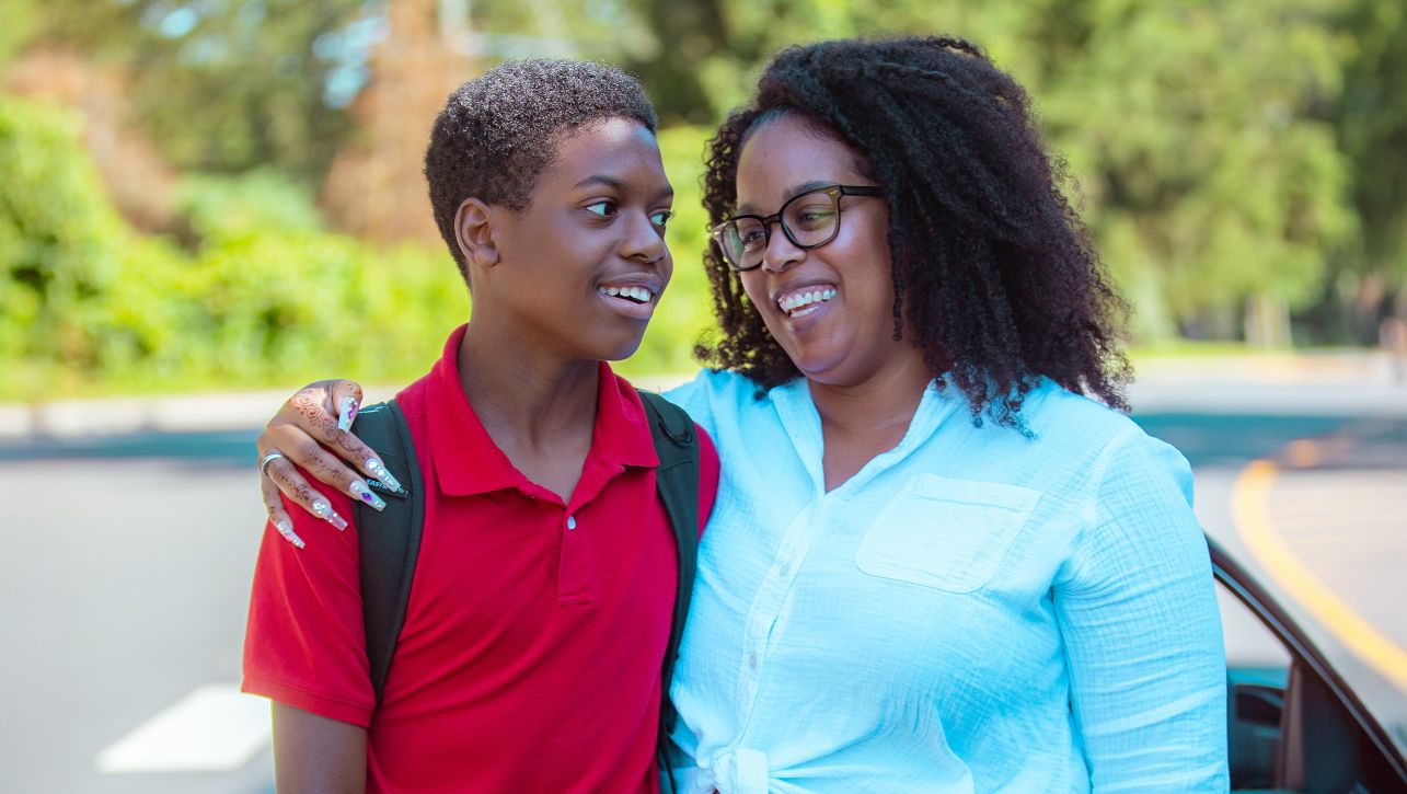 Young boy and his mother smiling with their arms around each other