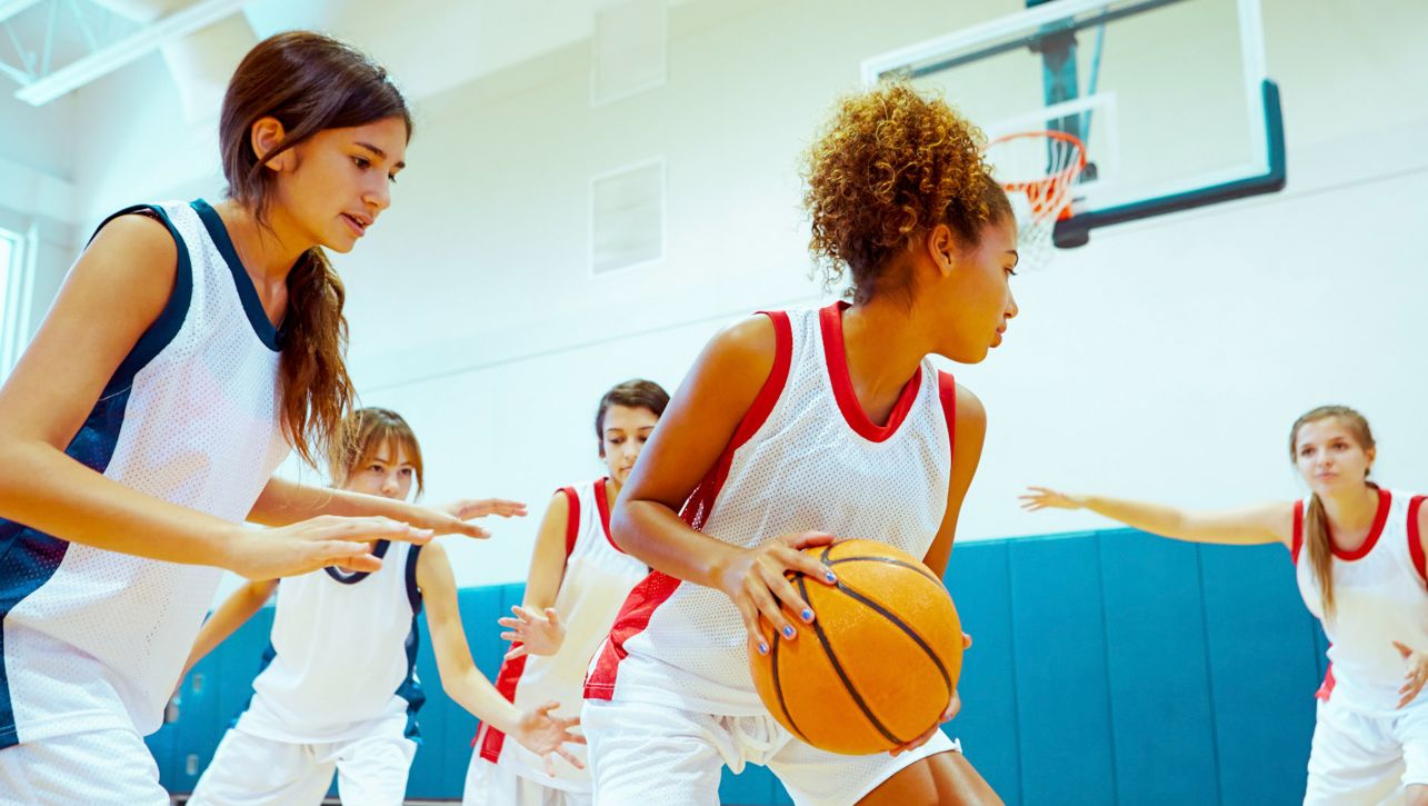 Girls playing basketball in school gym