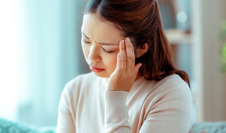 Woman with a headache, touching her forehead