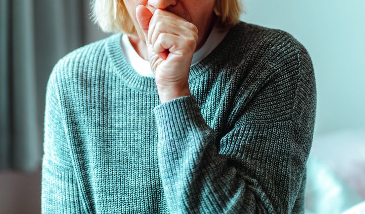 A person lightly coughing into their hand