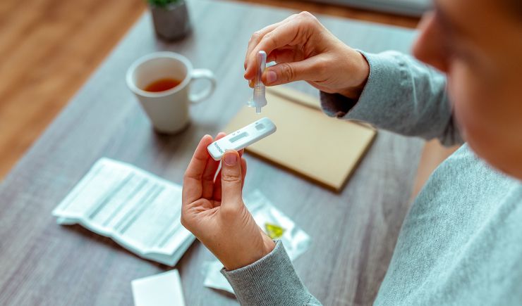 A person using a COVID test inside their home at the table