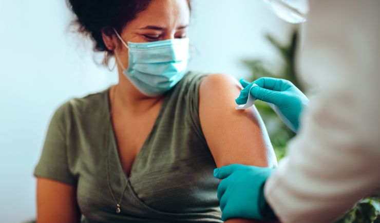Masked woman in a doctor's office getting prepped for a vaccine