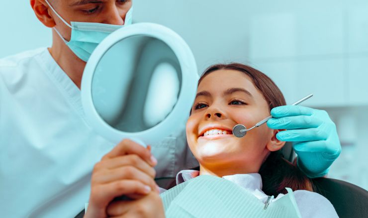 Child at dentist smiling at mirror looking at teeth