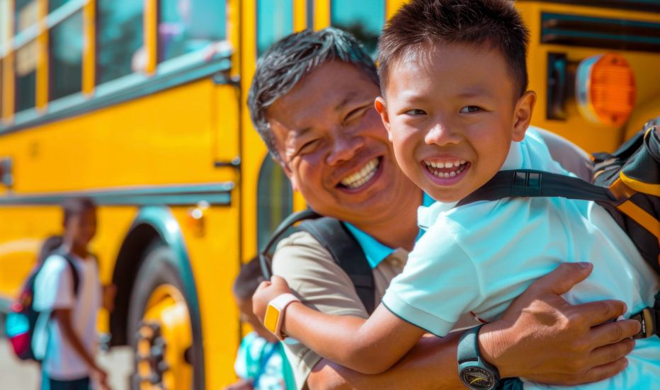 Father and son hugging each other outside of school bus