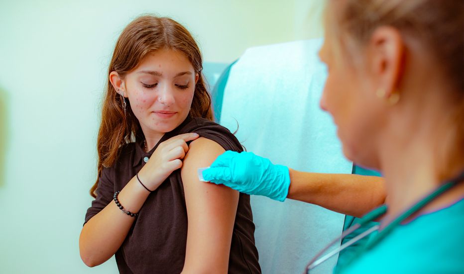 Young girl smiling while getting a vaccine from a nurse