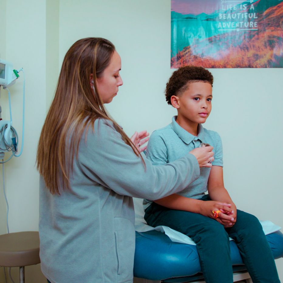 School nurse listening to students chest with stethoscope